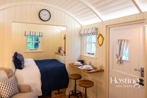 a bedroom with a bed and a clock on the wall at Red Kite Retreat - Pansy - Shepherds Hut 3 in Henley on Thames