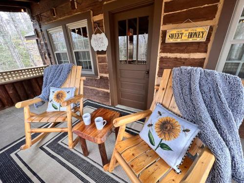 a patio with two chairs and a table on a porch at Boozy Bear Bungalow romantic cabin 5 mins 2 downtown with hot tub and fire pit in Gatlinburg