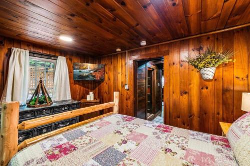 a bedroom with a bed in a wooden room at Boozy Bear Bungalow romantic cabin 5 mins 2 downtown with hot tub and fire pit in Gatlinburg
