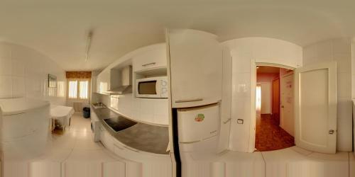 a white room with a kitchen with a microwave at Pensión Pamplonabeds in Pamplona