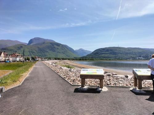two benches sitting on the side of a road next to a river at A view to Caol, Fort William in Fort William