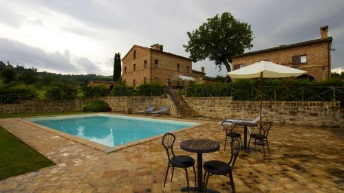 uma piscina com cadeiras, uma mesa e um guarda-sol em Villa Serena - Homelike Villas em SantʼAngelo in Pontano