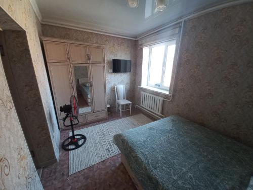 Habitación pequeña con cama y ventana en Hotel "Тихий Дом Трансфер" en Bishkek