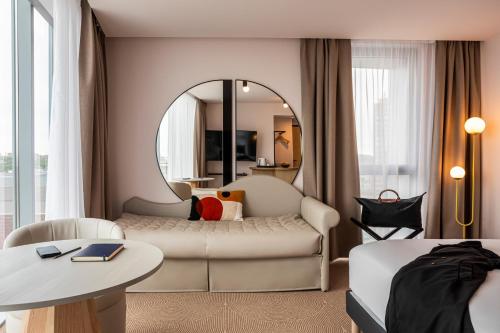 a living room with a couch and a mirror at Mercure Dunkerque Centre Gare in Dunkerque