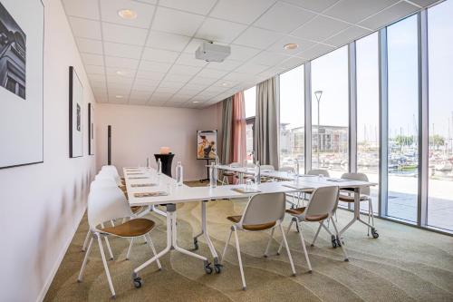 a conference room with tables and chairs and large windows at Mercure Dunkerque Centre Gare in Dunkerque