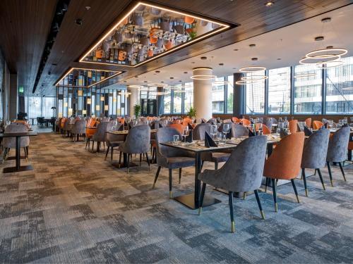 a dining room with tables and chairs and windows at Grand Plaza Hotel & Congress Center in Ljubljana