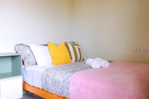 a bedroom with a bed with a pink and yellow pillow at Spacious and Cozy 1-Bedroom Condo at Brenthill in Baguio