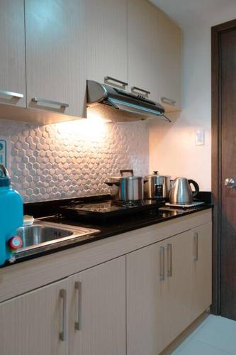 a kitchen with pots and pans on a stove at Spacious and Cozy 1-Bedroom Condo at Brenthill in Baguio