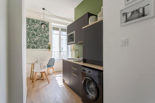 une cuisine avec une machine à laver et une table dans l'établissement Magnifique Studio - Lyon 3, à Lyon