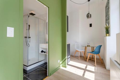 La salle de bains est pourvue de murs verts, d'une table et de chaises. dans l'établissement Magnifique Studio - Lyon 3, à Lyon