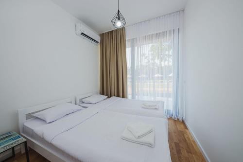 a bedroom with a white bed and a window at KOKO VILLAGE in Podgorica