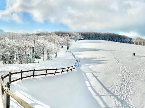 a snow covered field with a fence and people skiing on it at Duplex nuovo e grazioso in Capracotta
