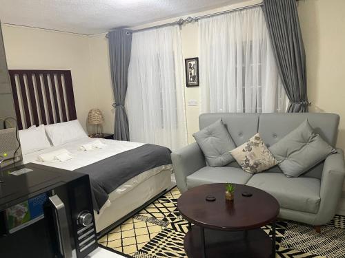 uma sala de estar com uma cama e um sofá em @Jackie’s Avondale 2 bed flat at Harrow court em Harare
