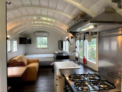 een keuken en een woonkamer met een bank en een fornuis bij Natuurhuisje Markelo, zeer compleet, met veel luxe in Markelo