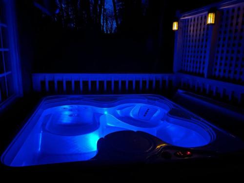a hot tub with blue lighting in a dark room at Boozy Bear Bungalow romantic cabin 5 mins 2 downtown with hot tub and fire pit in Gatlinburg