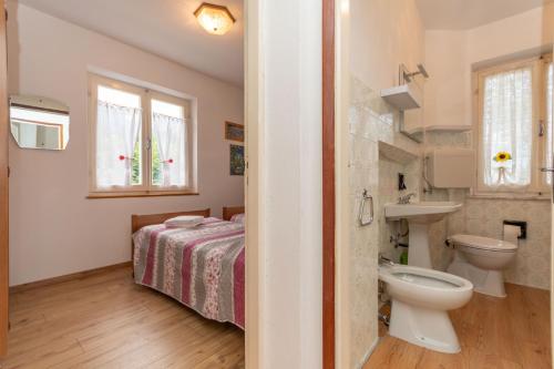 a bathroom with a bed and a toilet and a sink at Villa Elisena in Falcade