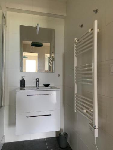 La salle de bains blanche est pourvue d'un lavabo et d'un miroir. dans l'établissement Grand rez de jardin-terrasse avec vue sur la mer - 2 chambres, à Blonville-sur-Mer