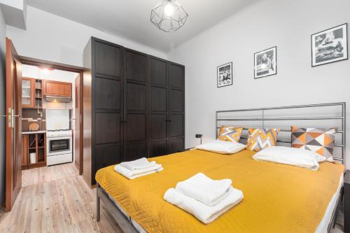 een slaapkamer met een geel bed en handdoeken bij Siewierska 17 by Homeprime in Warschau