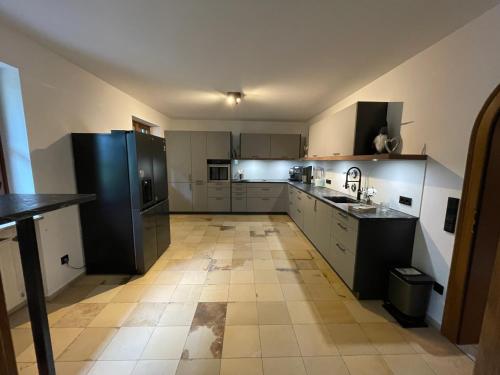 a large kitchen with white cabinets and black appliances at Ferienwohnung Bad Reichenhall (Nonn) in Bad Reichenhall