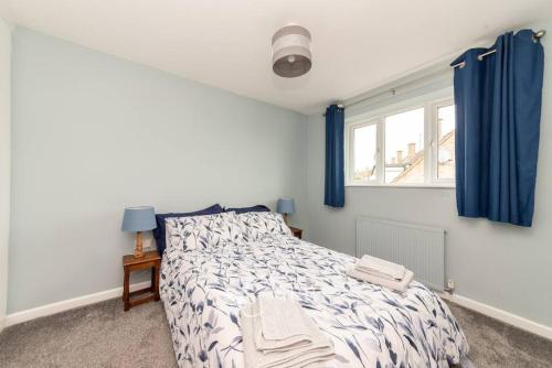 a bedroom with a bed with blue curtains and a window at Bellamy Road - 3 Bedroom home in Oundle