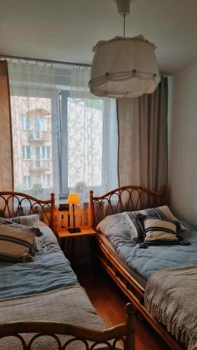 two beds sitting in a room with a window at Penthouse Mały Belweder in Ustrzyki Dolne
