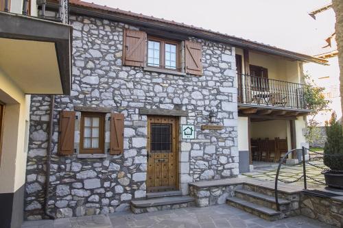 Casa rural Txikirrin Txiki - Selva de Irati في Villanueva de Aézcoa: منزل حجري بأبواب ونوافذ خشبية