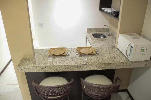 una cucina con bancone, forno a microonde e sgabelli di PIPAS BAY - Aparthotel Vista Mar a Pipa