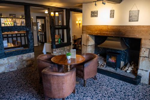 a room with a fireplace and a table and chairs at Bell Hotel by Greene King Inns in Tewkesbury