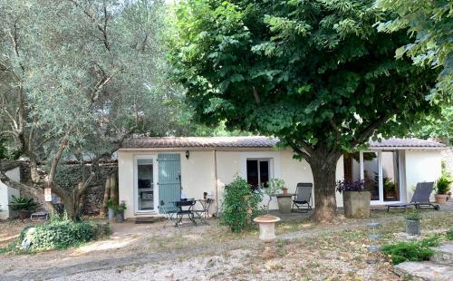 uma pequena casa branca com cadeiras e uma árvore em Mazet proche Golf em Nîmes