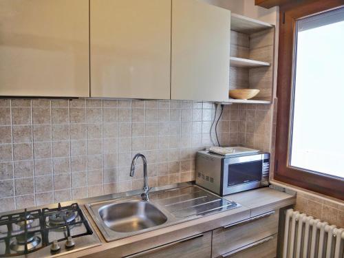 a kitchen with a sink and a microwave at Wind Rose House - bicamere, parcheggio fronte mare in Grado