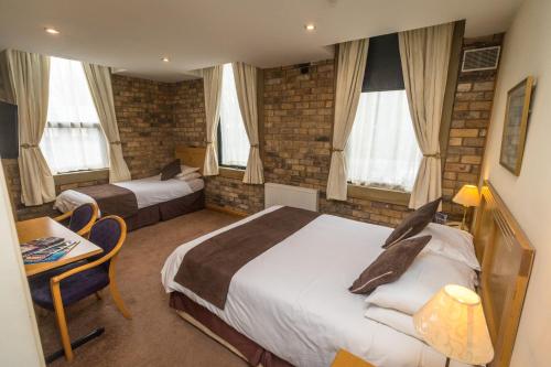 a hotel room with two beds and a table and chairs at The Sleepwell Inn in Workington