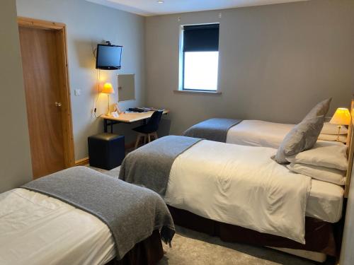 a hotel room with two beds and a desk at The Sleepwell Inn in Workington