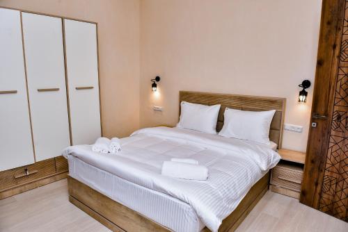 a bedroom with a large bed with white sheets and towels at Maestro Rest House Dilijan in Dilijan