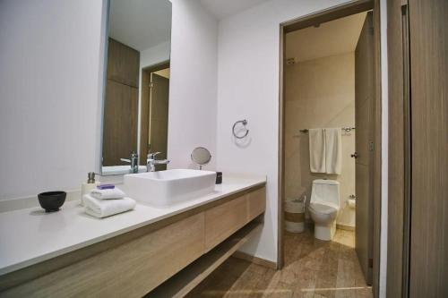 ein Badezimmer mit einem Waschbecken, einem WC und einem Spiegel in der Unterkunft Ultimate PH in a Prime spot with Pv Rooftop Pool in Tulum