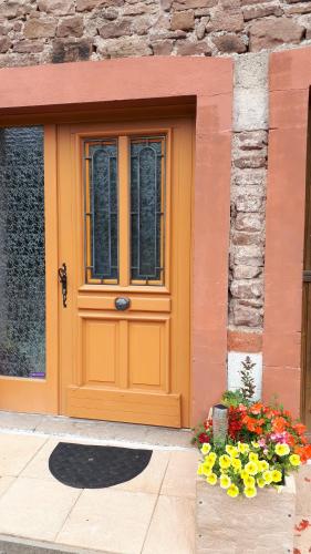 an orange door with flowers in front of a building at Studio à Ban de Sapt in Ban-de-Sapt