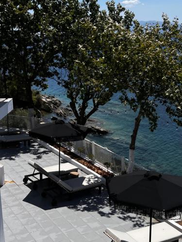 a patio with tables and umbrellas next to the water at Athos Cape in Pyrgadikia