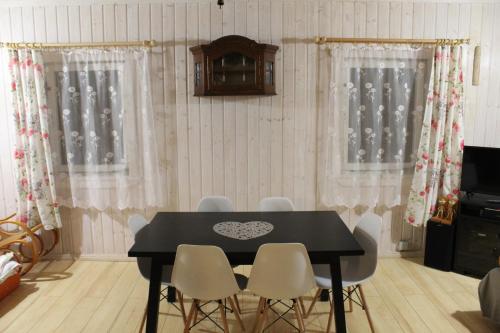 a dining room with a black table and white chairs at Niezapominajka in Bystrzyca Kłodzka