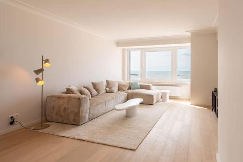 Sala de estar blanca con sofá y mesa en Luxe appartement met frontaal zeezicht bij Casino, en Ostende