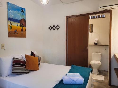 a bedroom with a bed and a toilet and a painting at Pousada Raiz Forte in Caraíva