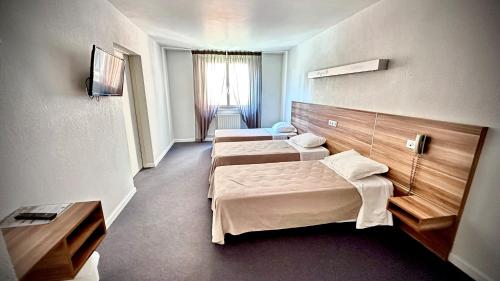 a hotel room with two beds and a window at Logis Hôtel Restaurant L'Europe in Marvejols