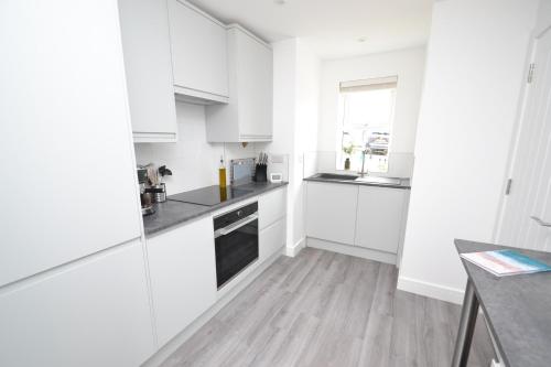 a white kitchen with white cabinets and a wooden floor at Cowes Town House in Cowes