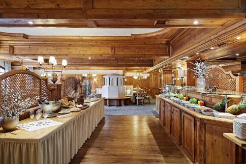 Habitación grande con techos de madera y una mesa larga con comida. en Lindner Hotel Oberstaufen Parkhotel, part of JdV by Hyatt, en Oberstaufen