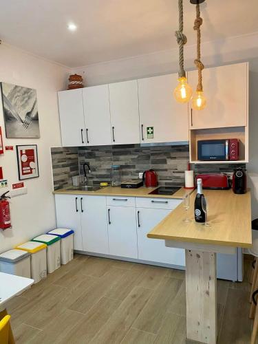 a kitchen with white cabinets and a wooden table at Alto do Moinho in Alcobaça