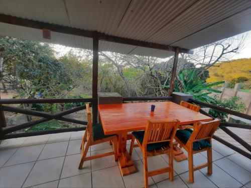 - une table et des chaises en bois sur une terrasse couverte dans l'établissement Highlands Creek Self Catering Accommodation, à Nelspruit