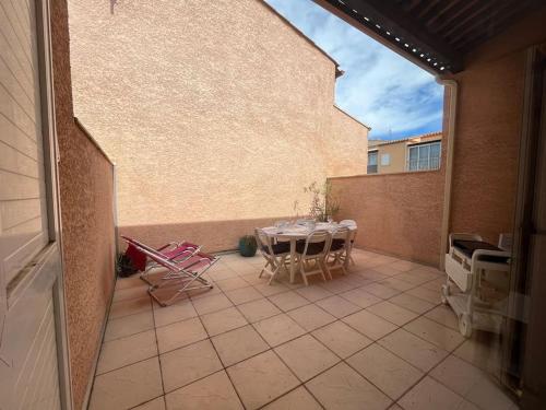 un patio avec une table et des chaises sur un balcon dans l'établissement Charmant pavillon pour 5-6 pers., au Cap d'Agde
