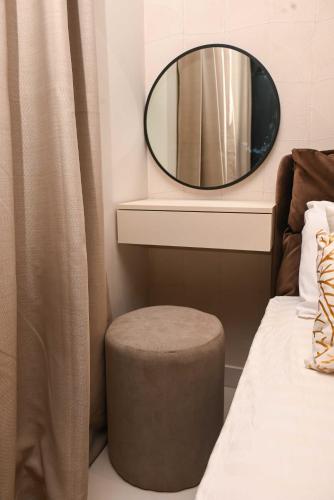 a bedroom with a mirror and a stool next to a bed at The Broadway @The Lennox in Accra