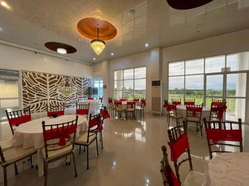 uma sala de jantar com mesas brancas e cadeiras vermelhas em Pilot Hotel powered by Cocotel em Alaminos