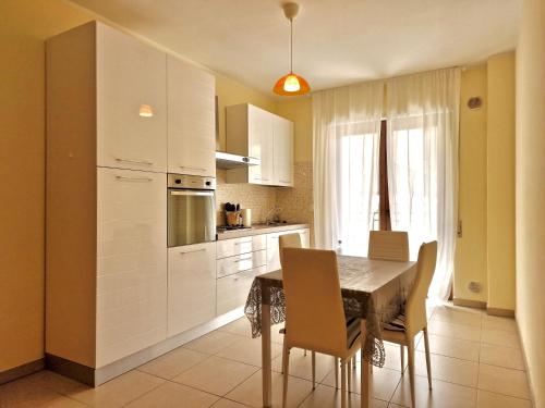 拉奎拉的住宿－La Chiostrina by TraMonti Apartments，一间带桌椅的厨房和一间带白色橱柜的厨房