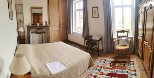 a bedroom with a bed and a chair and windows at Le Clos du Hesdre in Neufchâtel-Hardelot