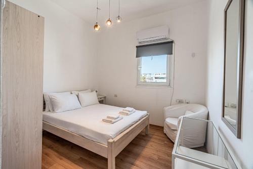 um pequeno quarto branco com uma cama e uma janela em Penthouse 3BR in Ben Yehuda By Holiday Rentals em Tel Aviv
